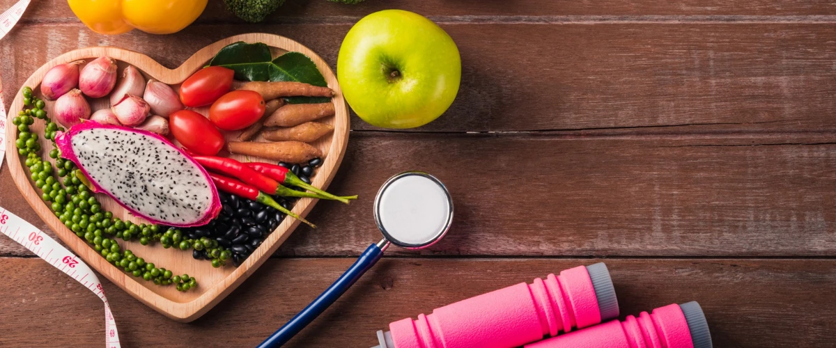 Healthy and balanced meal with exercise equipment and stethoscope on table.