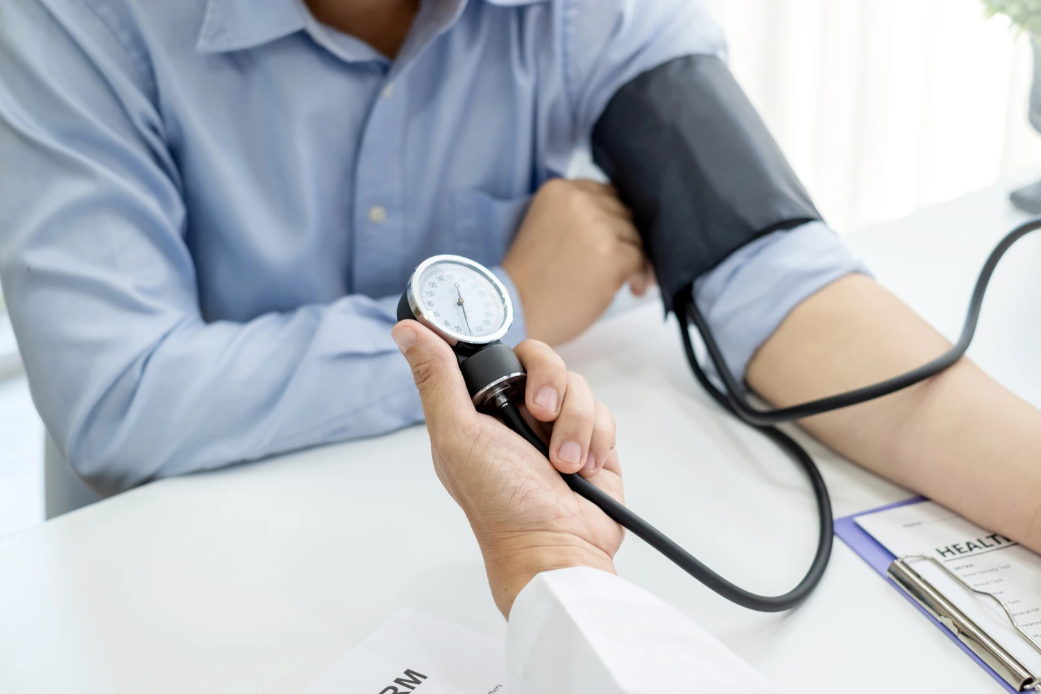 Doctor taking patient's blood pressure reading at clinic.