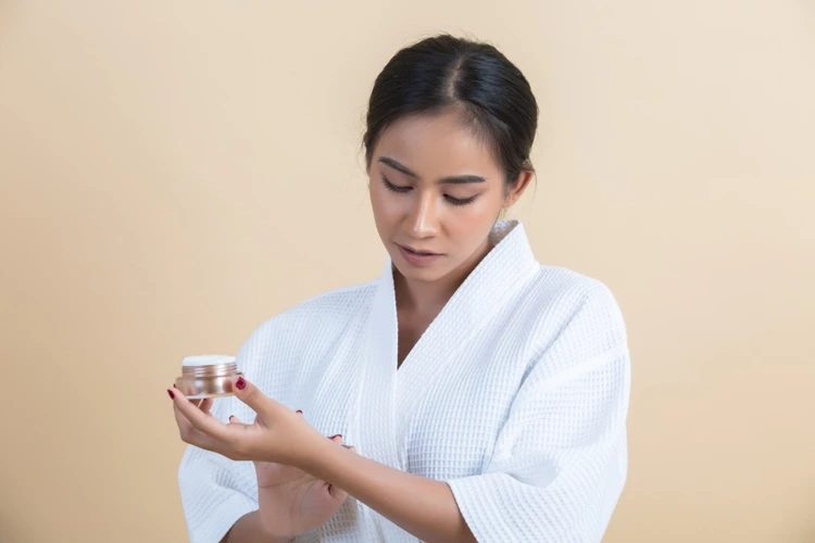 Lady applying cream on her wrists to treat her acne issues.