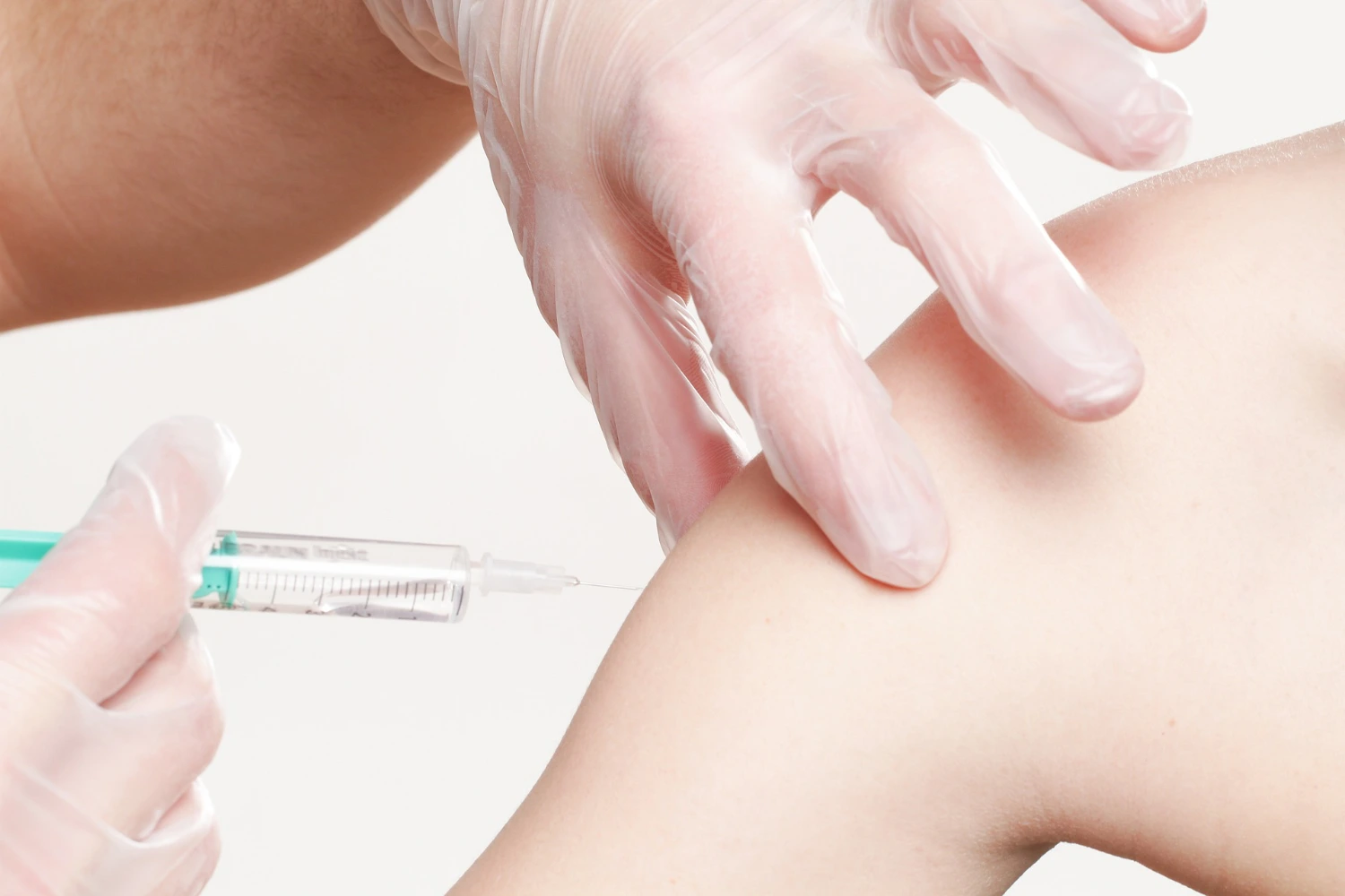 Doctor administering vaccination jab to patient at clinic.